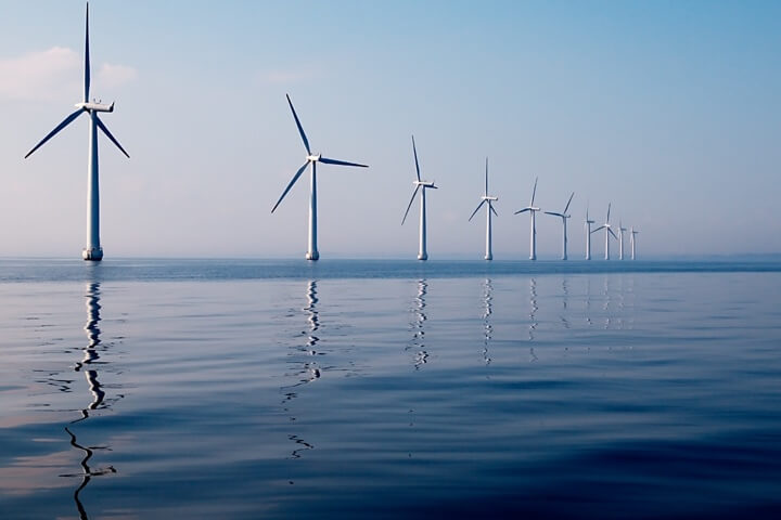 Reihe von Windkraftanlagen im Meer bei klarem Himmel – Symbol für nachhaltige Energiegewinnung und langfristige Umweltverantwortung.