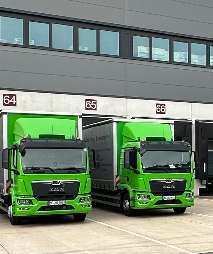 Zwei HSP-LKW vor dem firmeneigenen Logistikzentrum – Teil der integrierten Liefer- und Logistiklösungen für einbaufertige Präzisionskomponenten und Zeichnungsteile.