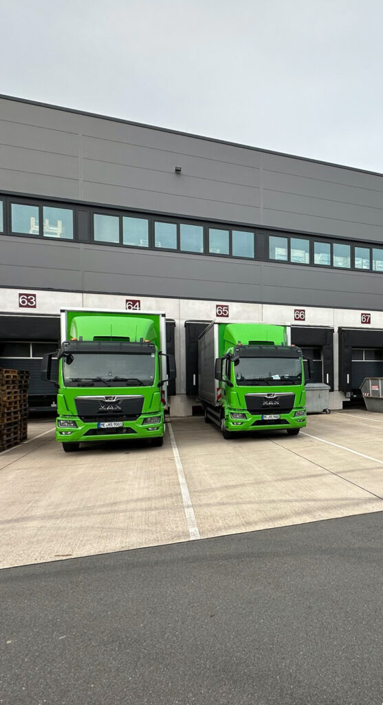 Zwei HSP-LKW vor dem firmeneigenen Logistikzentrum – Teil der integrierten Liefer- und Logistiklösungen für einbaufertige Präzisionskomponenten und Zeichnungsteile.