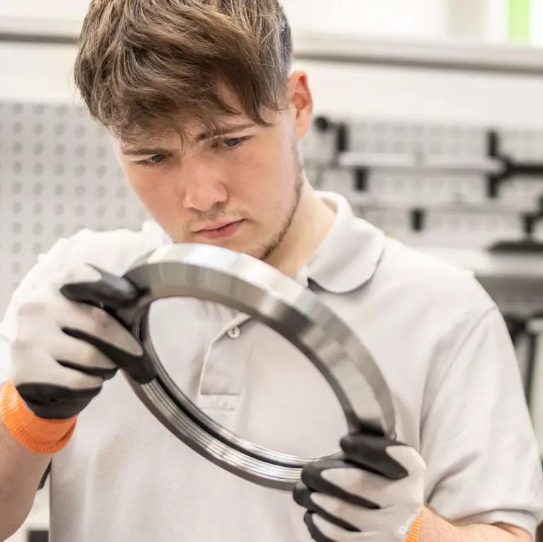 Ein HSP Auszubildender bei der visuellen Inspektion eines Werkstücks.