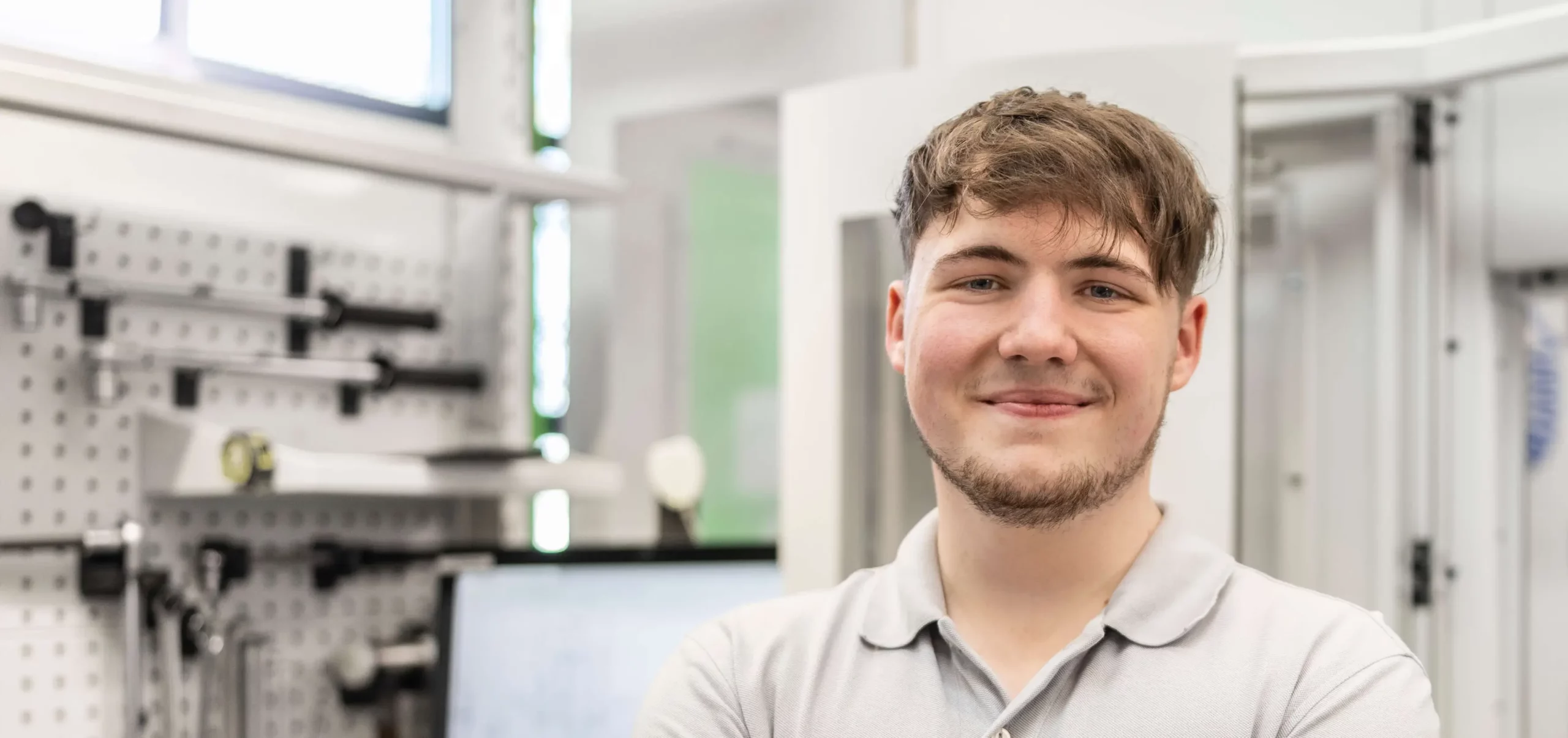 Ein HSP Auszubildender in der Fertigung lächelt frontal in die Kamera.