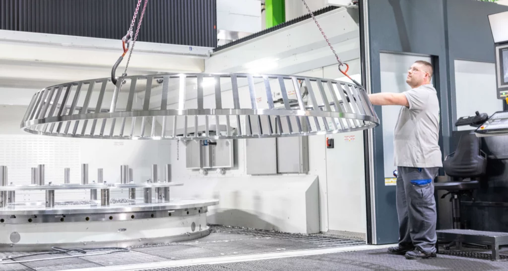 Ein HSP Mitarbeiter entnimmt einen XXL Wälzlagerkäfig aus der Produktionsanlage.